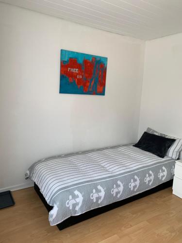 a bed in a white room with a picture on the wall at H4 Erdgeschoss in Nellingen