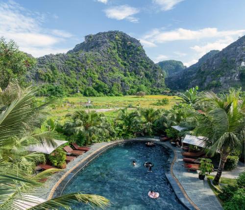 a pool in a resort with mountains in the background at Scenic Mountain Ecolodge Ninh Binh in Ninh Binh