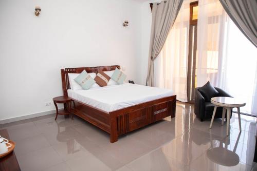 a bedroom with a bed and a chair and a window at Tulivu Resort in Kituoni