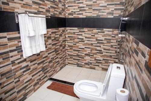 a bathroom with a toilet and a tiled wall at Tulivu Resort in Kituoni