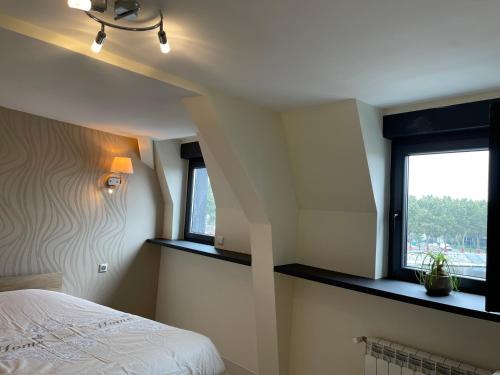 a bedroom with a bed and two windows at Le centre in Montluçon