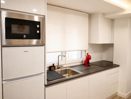 a kitchen with white cabinets and a stainless steel refrigerator at Sisargas Playa in Malpica