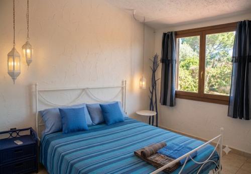 a bedroom with a bed with blue sheets and a window at Villa stella di mare in Capitana