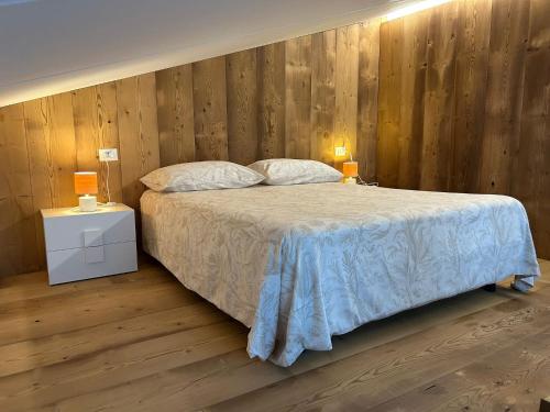 a bedroom with a bed with a wooden wall at Lodge Valchiavenna in Verceia