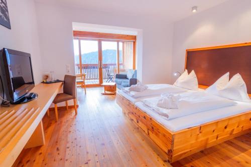a bedroom with a bed and a desk with a television at Hotel Ramsauhof Zimmer Appartement Pool & Wellness in Ramsau am Dachstein