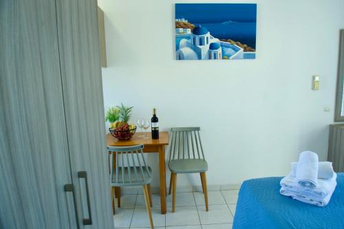 a bedroom with a table with two chairs and a bottle of wine at Johnhara Studios & Apartments in Ialysos