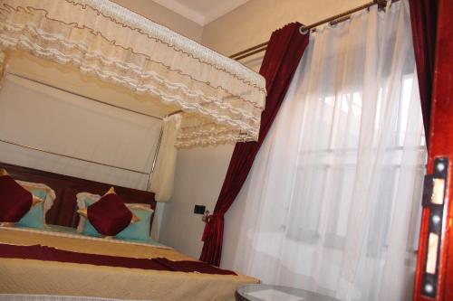 a bedroom with a canopy bed and a window at Crown Suites Motel in Masaka