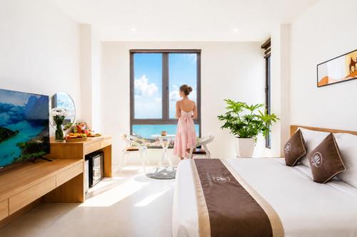 a woman standing in a bedroom with a large window at Quy Nhon Sea Hotel in Quy Nhon