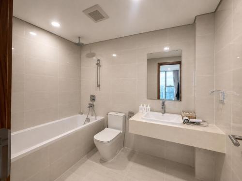 a bathroom with a toilet and a tub and a sink at Eco Green Apartment Residence District 7 in Ho Chi Minh City
