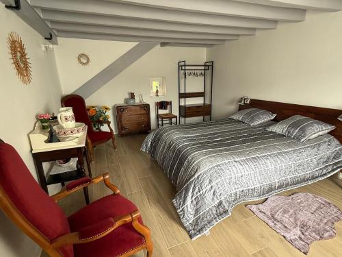 a bedroom with a bed and a chair at La ferme des Gabelles in Saint-Benoît-sur-Loire