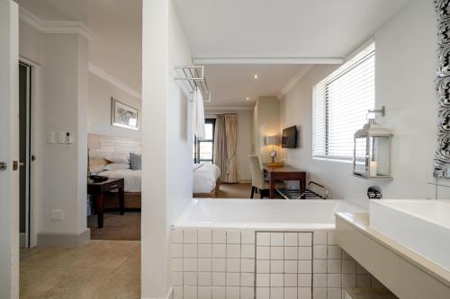 een witte badkamer met een badkuip en een slaapkamer bij Harbour House Hotel - Harbour Square in Hermanus