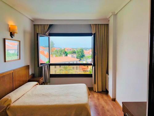 ein Schlafzimmer mit einem Bett und einem großen Fenster in der Unterkunft Hotel Herbiña 3000 in Cambados