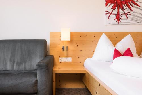a bedroom with a couch and a bed and a desk at Hotel Garni Frommes in Fiss