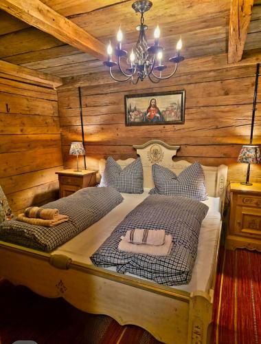 a bedroom with a bed with a chandelier and wooden walls at Augihütte in Abtenau
