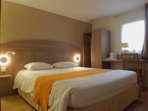 a bedroom with a large bed with an orange blanket at The Originals City, Hôtel Le Gayant, Douai in Douai