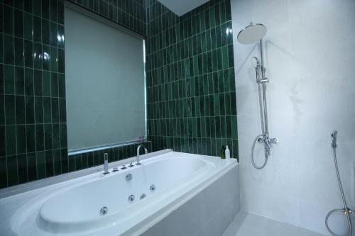 a green tiled bathroom with a tub and a mirror at Cloud Rose Villa Hoi An in Danang