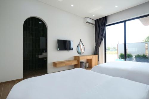a bedroom with two beds and a tv and a window at Cloud Rose Villa Hoi An in Danang
