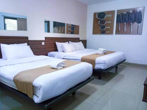 a hotel room with two beds in a room at De La Charis Hotel in Kediri