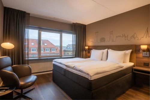 a hotel room with a bed and a chair and a window at Radisson Blu Limfjord Hotel, Aalborg in Aalborg