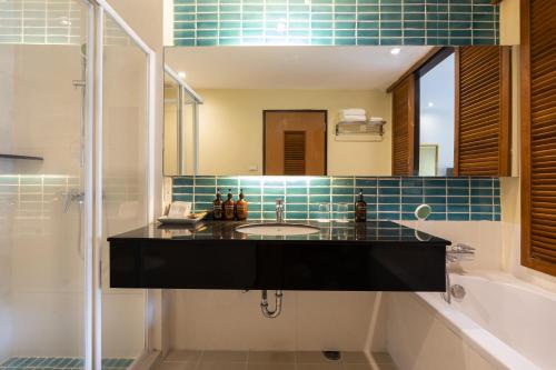 a bathroom with a sink and a tub and a mirror at Naithonburi Beach Resort in Nai Thon Beach