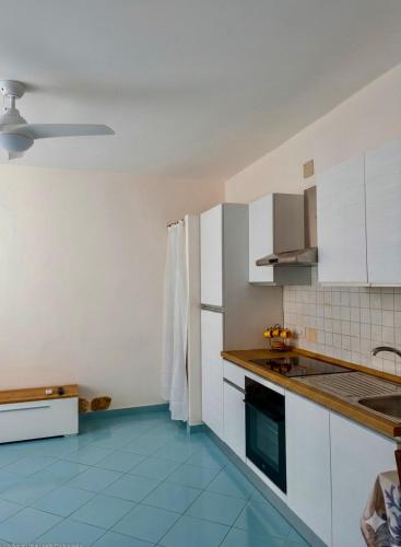a kitchen with white cabinets and a blue tile floor at Onda Blu House in Procida