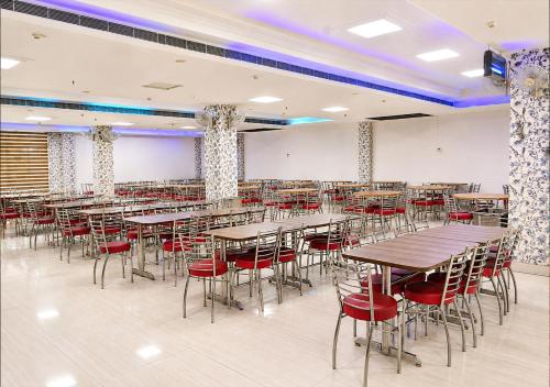 a dining room with tables and red chairs at Joygaon Hotel & Resorts in Jhajjar