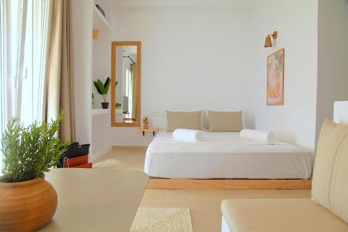 a white bedroom with a bed and a mirror at To Nisaki in Loutraki