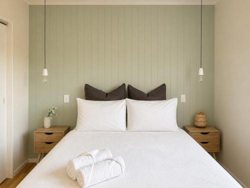 a bedroom with a white bed with two towels on it at Waikanae Beach Abode in Waikanae