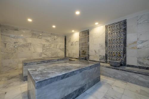 a bathroom with a stone wall with a large tub at Azure By Yelken Hotel in Turgutreis