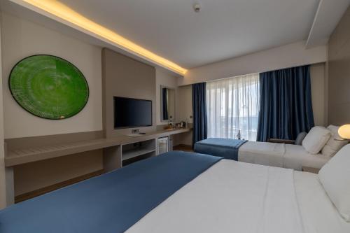a hotel room with a large bed and a television at Azure By Yelken Hotel in Turgutreis