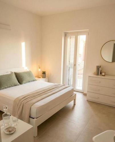 a white bedroom with a large bed and a table at Il PuntoPiu'Alto in SantʼAntìoco