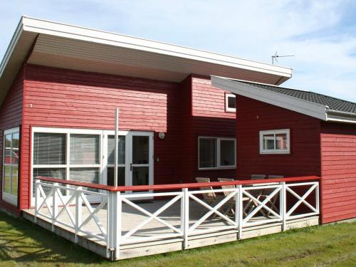a red house with a large deck in front of it at Danland Rø Golf Houses in Gudhjem