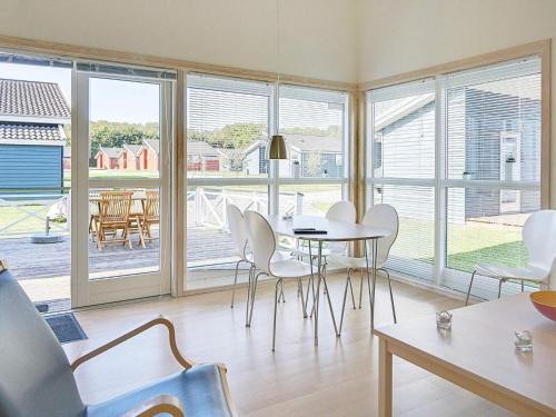 a dining room with a table and white chairs at Danland Rø Golf Houses in Gudhjem