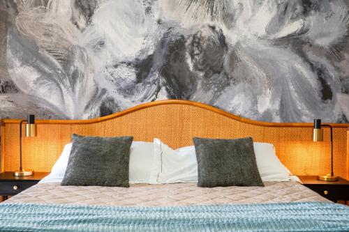 a bed with two pillows in front of a painting at Hotel Baia di Talamone in Talamone