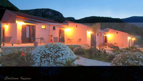 a house with lights on the side of it at Hotel Antica Cascina Del Golfo in Scopello