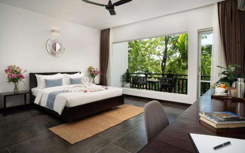 a bedroom with a bed and a desk and a window at Indochine Serenity Boutique in Siem Reap