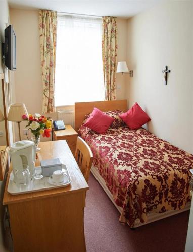 a hotel room with a bed and a table at St Winefride's Guesthouse in Holywell
