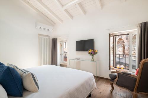 a white bedroom with a bed and a tv at Conte Manfredo and Donna Angelina Apartments with Breathtaking Arena Views in Verona in Verona