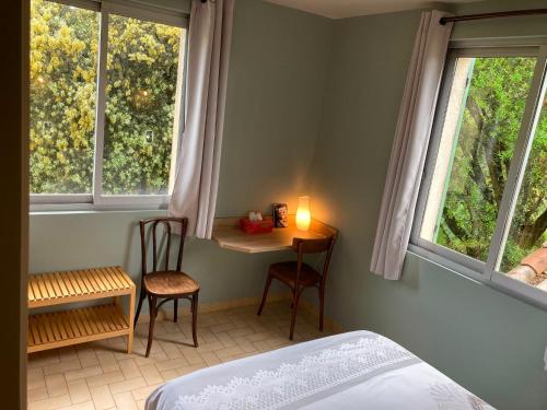 a bedroom with a table and chairs and two windows at "Le Pigeonnier" chambre d'hôte in Piégros-la-Clastre