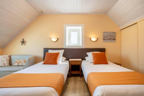 two beds in a small room with a couch at Chambres D'hôtes De Kerantum in Mahalon