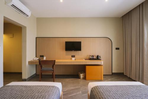 a room with two beds and a desk with a television at Legong Keraton Beach Hotel in Canggu