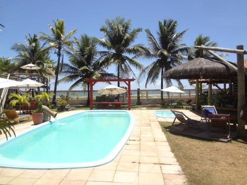 a pool with chairs and umbrellas and palm trees at Pousada Terceiro Espaço in Guaibim