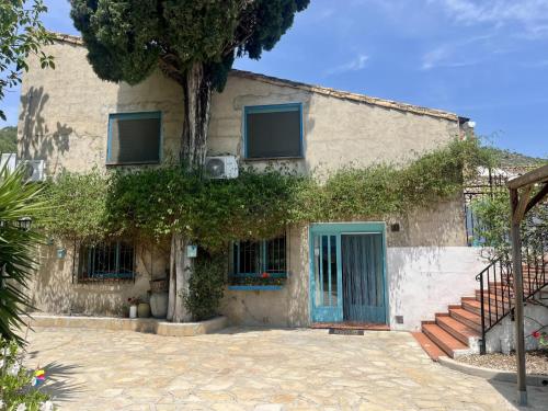 a house with a blue door and a tree at B&B Casa Ellie in Tormos