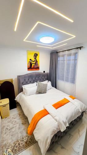a bedroom with a large bed with an orange blanket at LIBERTY TOWERs in Lower Kabete