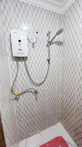 a shower in a bathroom with a white tiled wall at LIBERTY TOWERs in Lower Kabete