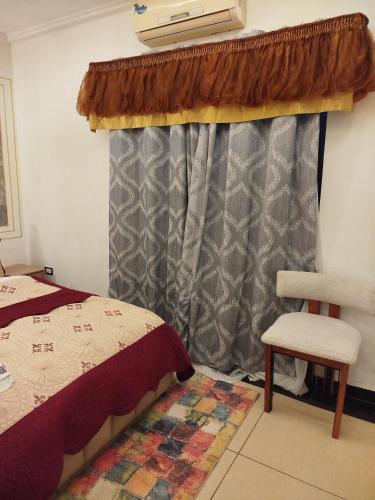 a bedroom with a bed and a chair and a window at Mon Nid d'Or ABIDJAN CI in Abidjan