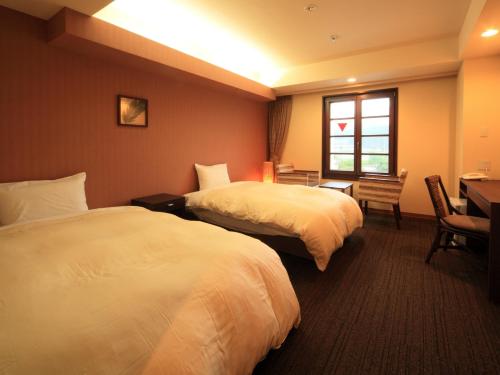 a hotel room with two beds and a desk and a window at Nikko Station Hotel Classic in Nikko