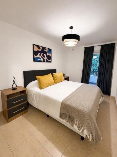 a bedroom with a bed with yellow pillows and a table at Paramont Rosario 4 in Rosario de la Frontera