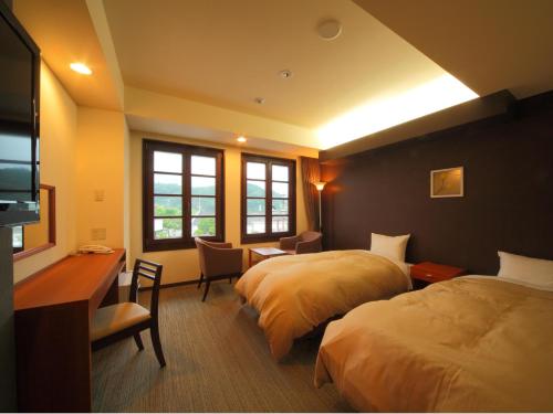 日光市にある日光ステーションホテル　クラシックのベッド2台とデスクが備わるホテルルームです。