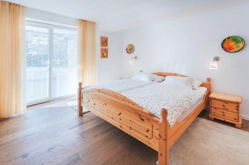 a bedroom with a wooden bed and a large window at Apartments Poklukar in Bled